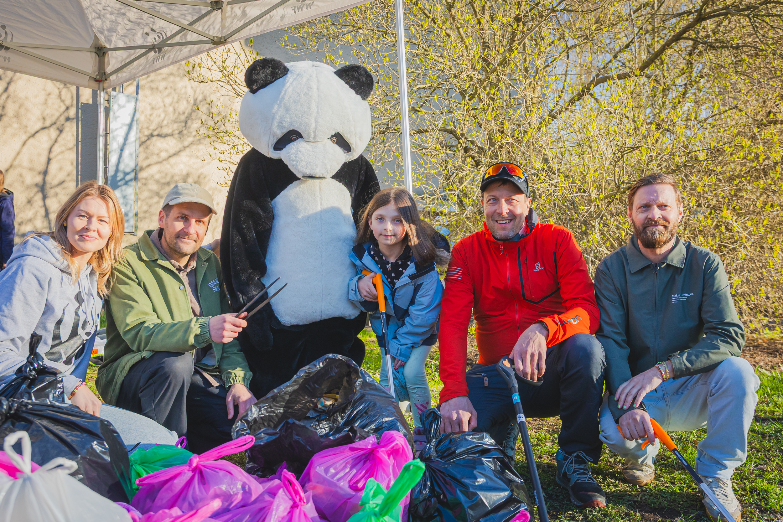 Talkoiden järjestäjät poseeraavat rivissä WWF-pandan ja kerättyjen roskien kanssa.